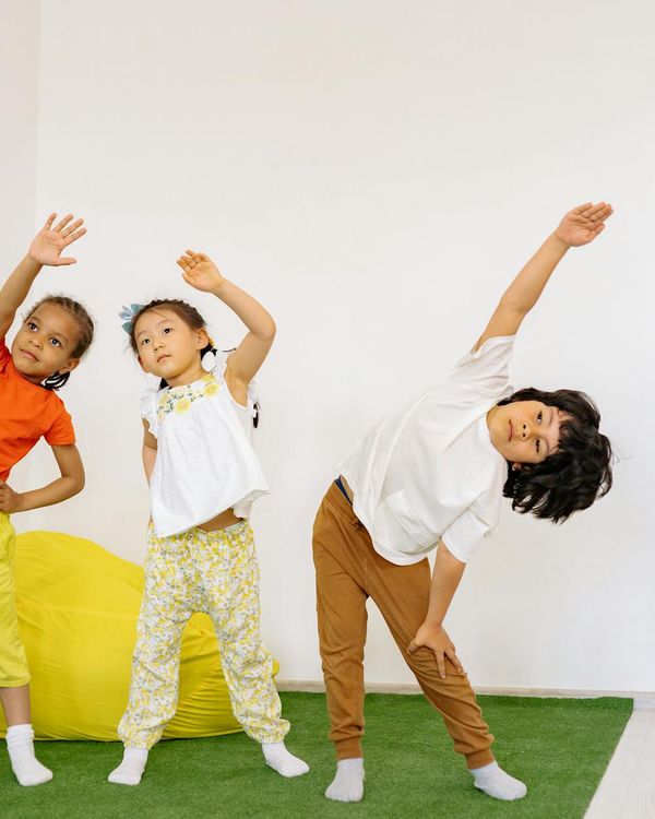 A diverse group of kids laughing during a yoga class.